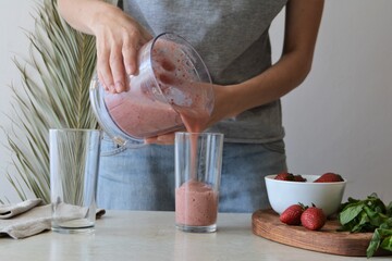 Woman cooking a strawberry and banana smoothie. Healthy food concept