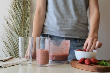 Woman holds a glass of strawberry smoothie. Healthy food concept