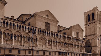 Obraz premium Ferrara, Italy. Loggia dei Merciai and cathedral bell tower. Sepia photo, vintage atmosphere.