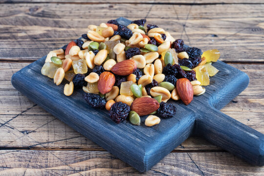 A mixture of nuts and dried fruits on a wooden chopping board, rustic background. Concept of healthy food.