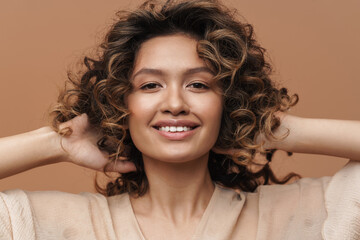 Young curly hispanic woman smiling and touching her hair