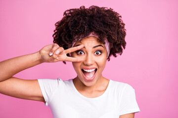 Photo of young happy excited cheerful smiling african woman showing v-sign on eye isolated on pink color background