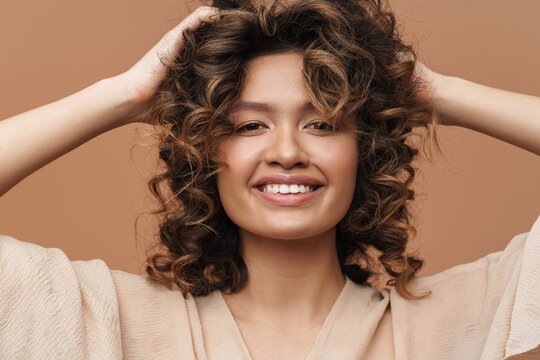 Young Curly Hispanic Woman Smiling And Touching Her Hair