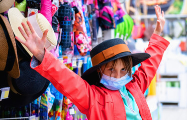 Naklejka na ściany i meble Young pretty girl posing with a hat against the background of shelves of a fashion. She having fun and she is happy as she tries on the hat.