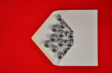 Online delivery. Postal envelope and metal nuts on a red background.
