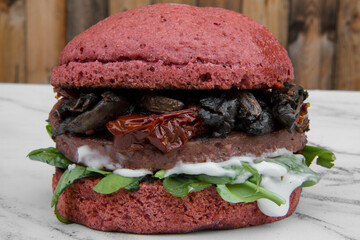 Vegetarian cuisine. Plant based. Closeup view of not co burger with beets bread, mushrooms, sun...