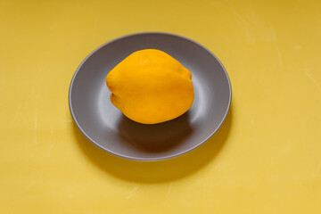 Colors of the year 2021. quince in a gray plate on a yellow background