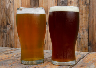 Brew. Closeup view of two pints of beer on the pub wooden table with a wooden background. A golden...