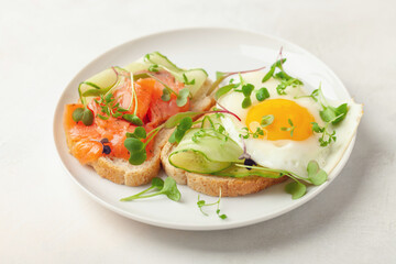 Toast with cucumber, salmon and egg in a plate on the table