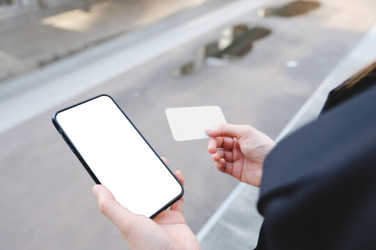 Woman hand holding blank credit card and using cell phone on white .Top view with copy space.