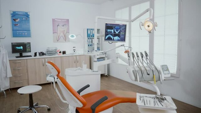 Close up revealing shot of stomatology orthodontic hospital office room with nobody in it prepared for healthcare treatment. Medical cabinet with teeth xray images on monitor and dentistry tools