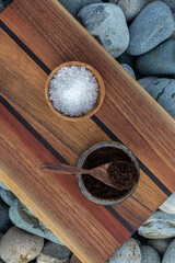 Preparing homemade coffee scrub with himalayan  salt on a wooden board on a background of sea pebbles - stock photo