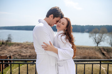A couple in white bathrobes enjoying the morning in a countryside house