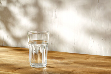 Glass of water on table and wall with shadows 