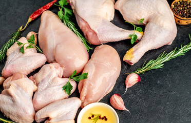 Different parts of chicken for barbecue with breast, legs and wings on stone background
