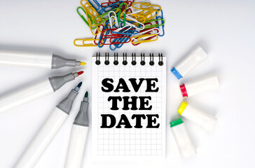 On the table are markers, paper clips and a notebook with the inscription - Save the date