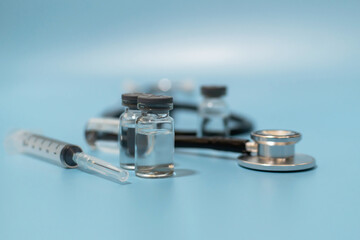 Obraz premium Coronavirus vaccine bottle, stethoscope and medical equipment with copy space on blue background, virus prevention, vaccination, medical technology, research laboratory, covid-19 vaccine concept