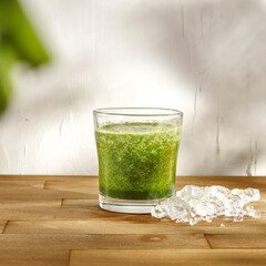Green glass on wooden and white wall 