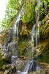 Obraz premium Beautiful waterfall in green forest in jungle. Jungle landscape with flowing red water of waterfall at deep tropical rain forest. National Park Old Mountain, Serbia