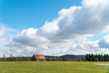 Wolken, Wiese und Wald mit Scheune