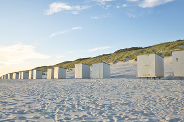 Fototapeta na wymiar Horizontal view on a beach with a row of beach cabins at sunset in spring. North sea beach with dunes in Zeeland on a sunny day. Copy space.