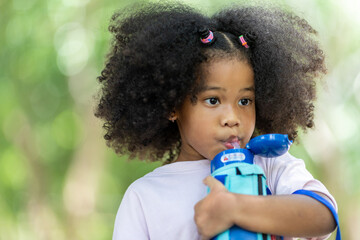 Children holding water plastic bottles and looking before a drink at outdoor. food and drink...
