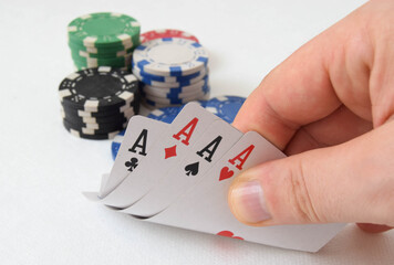 Close-up of mans hand showing his cards with four aces playing poker. Concept of gambling.