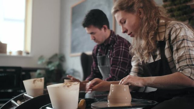 Potter masterclass, Man and woman are working with pottery wheel making pots during master class for adults, creative craftsman hobby. DIY Leisure activities and craftsmanship concept.