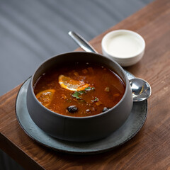 Pot of hodge podge on wooden table. Traditional rustic broth with meat, vegetables and olives seasoned with lemon.