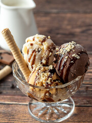 Chocolate, cream and caramel Roma ice cream in a glass bowl with hazelnut and chocolate sauce poured over it.