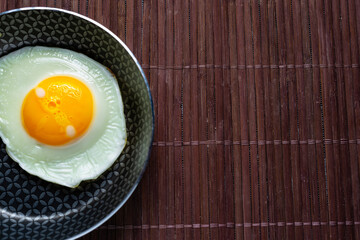 Frying pan with fried egg on a bamboo table