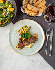 Grilled beef tenderloin steak on a ceramic plate with butter and thyme. Filet Mignon recipe with vegetables