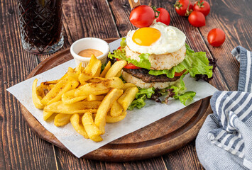 Korean burger with sunny side up egg, rice and fried fries on wooden background