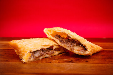 Open meat pastry, with red background and wood background, chroma typical Brazilian food