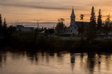 Fototapeta na wymiar Silhouetted cityscape downtown Fairbanks over Chena river at summer sunset