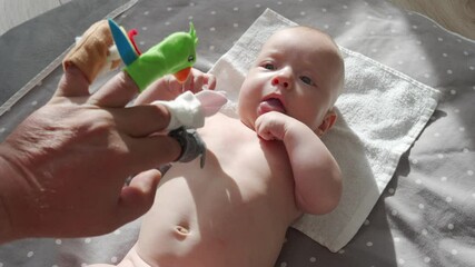 Father and his baby boy playing with finger puppet toys, three month old baby looking at father hand with finger puppets. High quality 4k footage