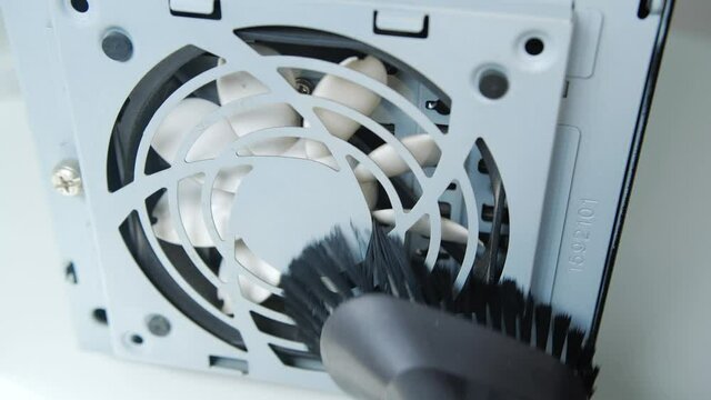 Concept PC service. Cleaning white computer fan with hoover.