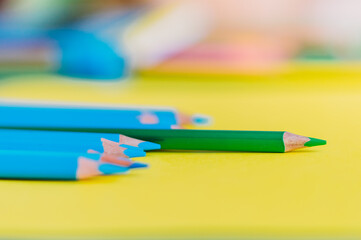 Sharpened blue pencils andone green pensil on a yellow background.