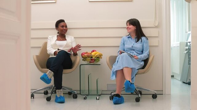They sitting waiting for the doctor's appointment. They talk, exchange messages. Call waiting. Communication of women in anticipation. Fruit on the table.