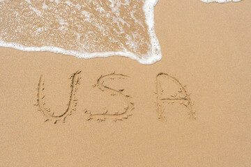 Word USA handwritten on the sand of beach