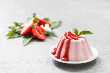 Dessert, creamy strawberry pudding with sauce on a plate on a light background