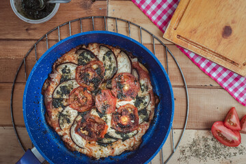 Vegetable pizza made in a blue skillet on a rustic wooden table