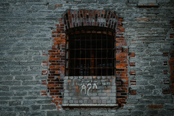 Fototapeta na wymiar An old window in the center of an old stone prison. The window is broken. Scary