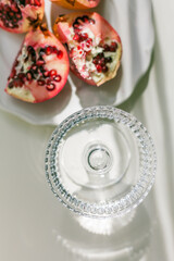 The background is white with shadows from a crystal glass, pomegranate.