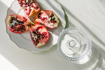 The background is white with shadows from a crystal glass, pomegranate.