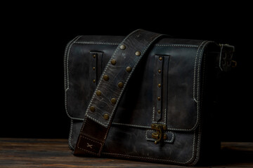 Retro style dark leather messenger bag with rivet straps.