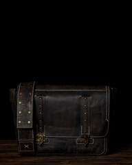 Retro style dark leather messenger bag with rivet straps.