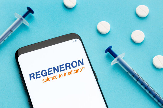 Galicia, Spain; June 8, 2020 : Smart phone showing Regeneron logo on screen and pills and syringe on blue background