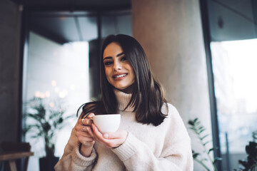 Positive woman enjoying coffee in cafe