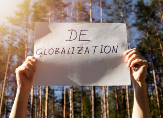 Deglobalization and reverse globalization concept. Word on paper poster in male hands with forest...